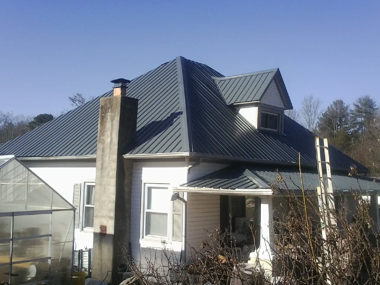 Dark blue standing seam metal roof on a white farmhouse with dormer — Slate & Tile Roof Repair by Roofing Brothers in Pendleton
